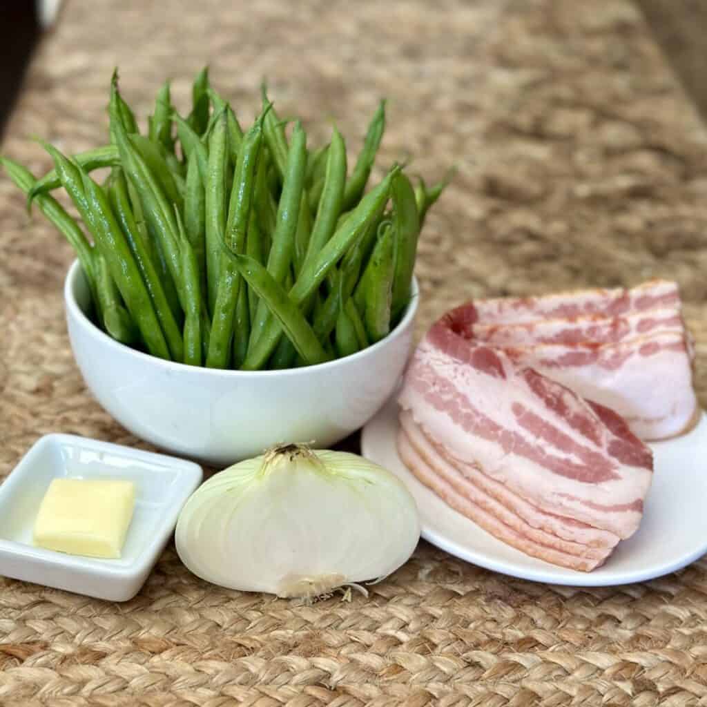 The ingredients to make greens beans with bacon and onion.
