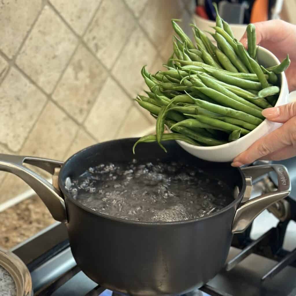 Adding green beans to boiling water.