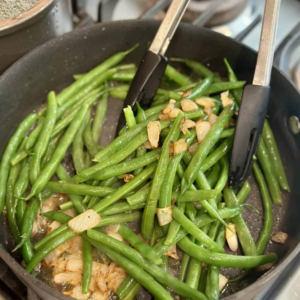 Sautéing green beans in a skillet.