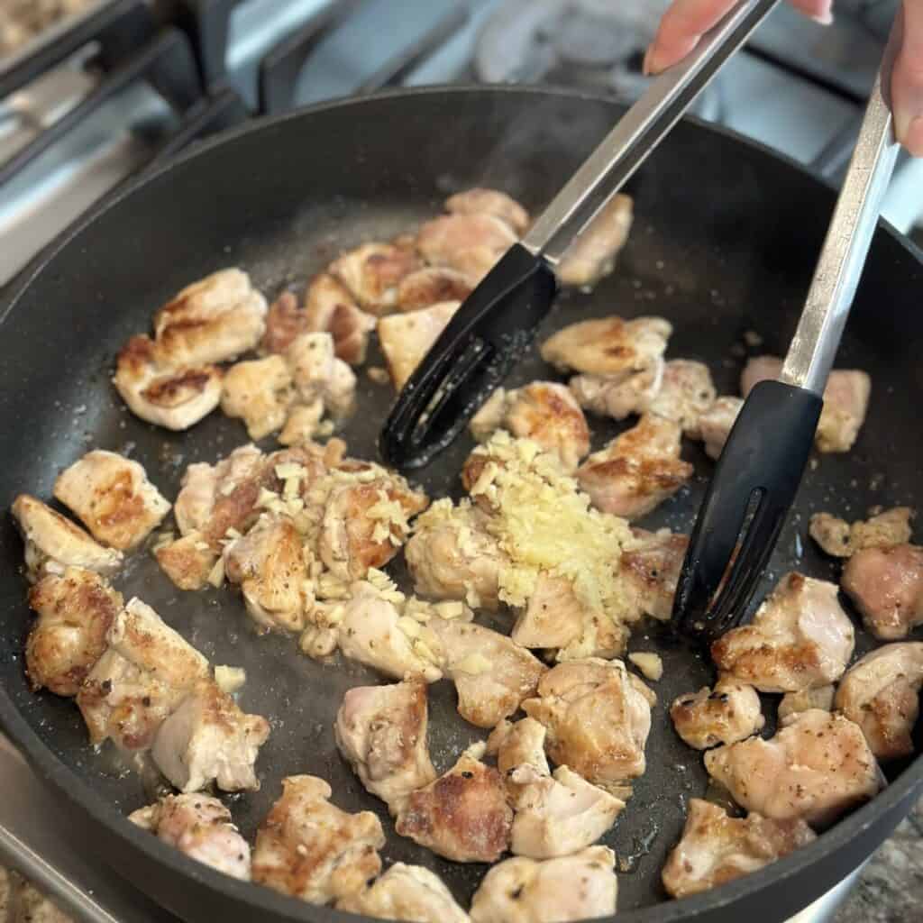 Cooking chicken with garlic and ginger in a skillet.