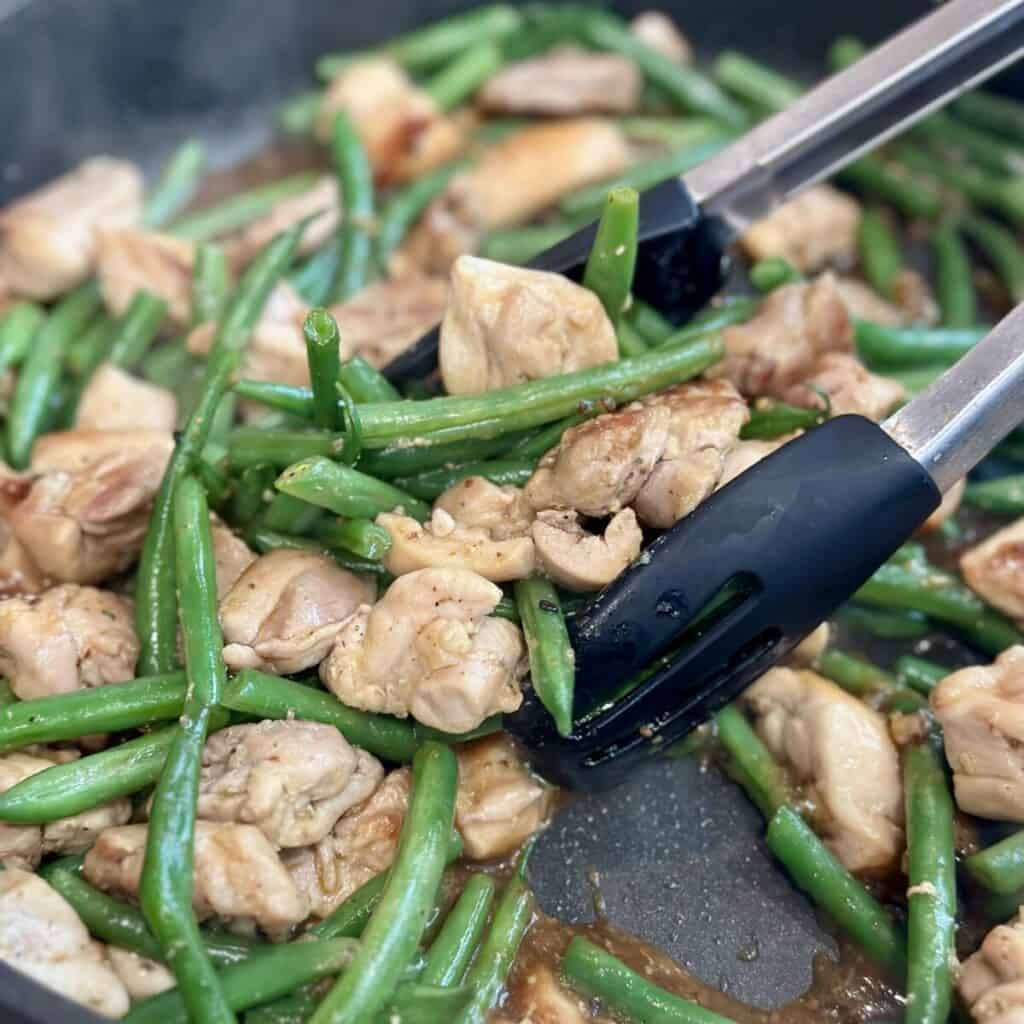 Sautéing chicken and beans in a pan.