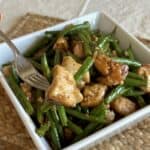 A bowl of cooked chicken and green beans.