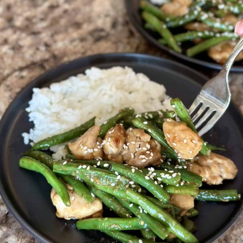 A plate of rice and chicken and green beans.