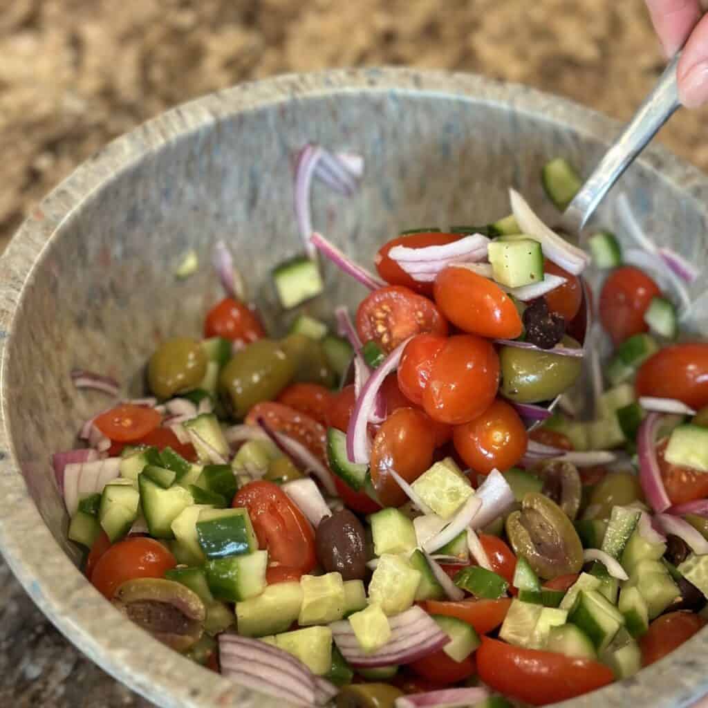 Mixing together ingredients for a Mediterranean Tomato Cucumber Salad.
