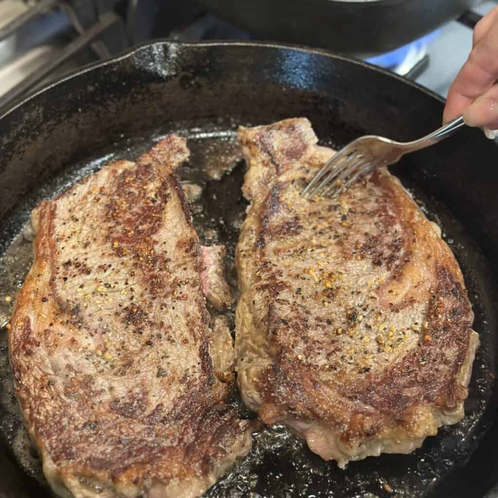 Searing ribeyes in a skillet.