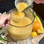 Dipping pineapple punch in a cup.