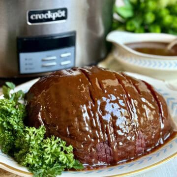 A slow cooker honey-glazed ham on a platter.