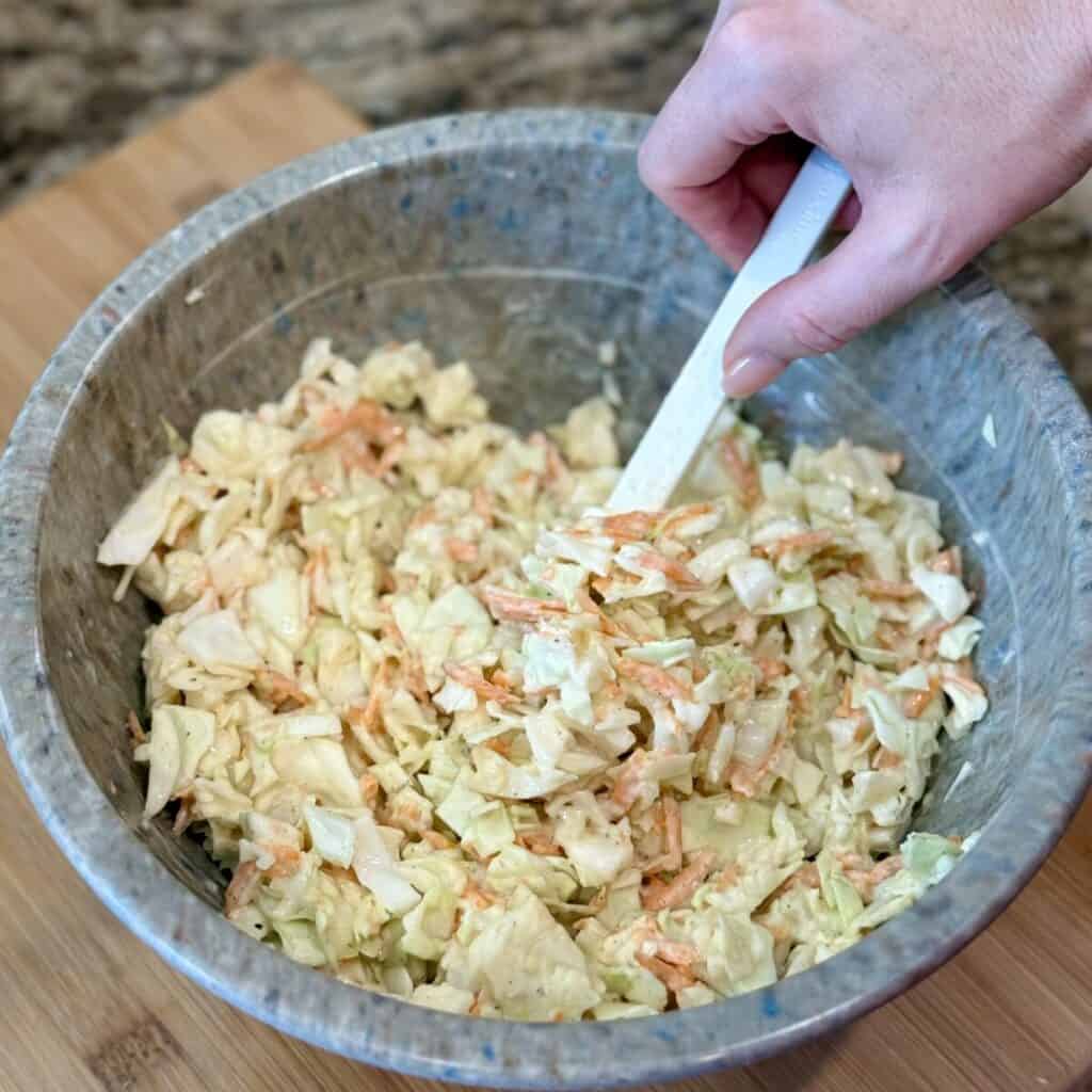 Stirring together KFC copycat coleslaw in a bowl.