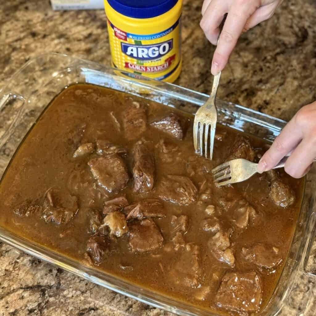 Shredding apart roast in gravy.