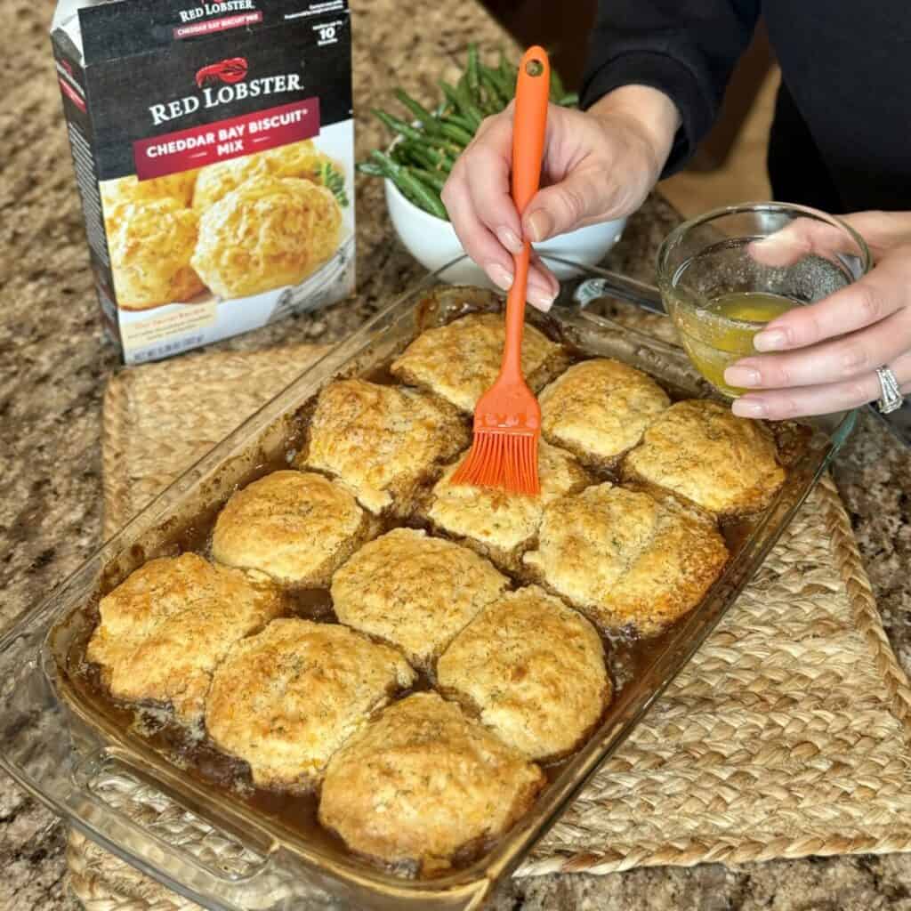 Brushing melted butter on beef cobbler.