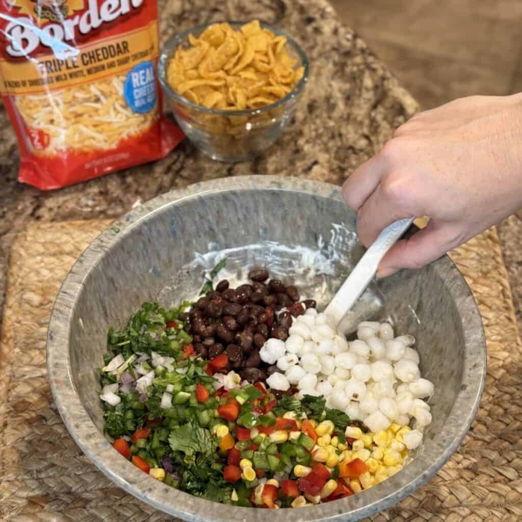 Mixing the ingredients together for corn chip salad.