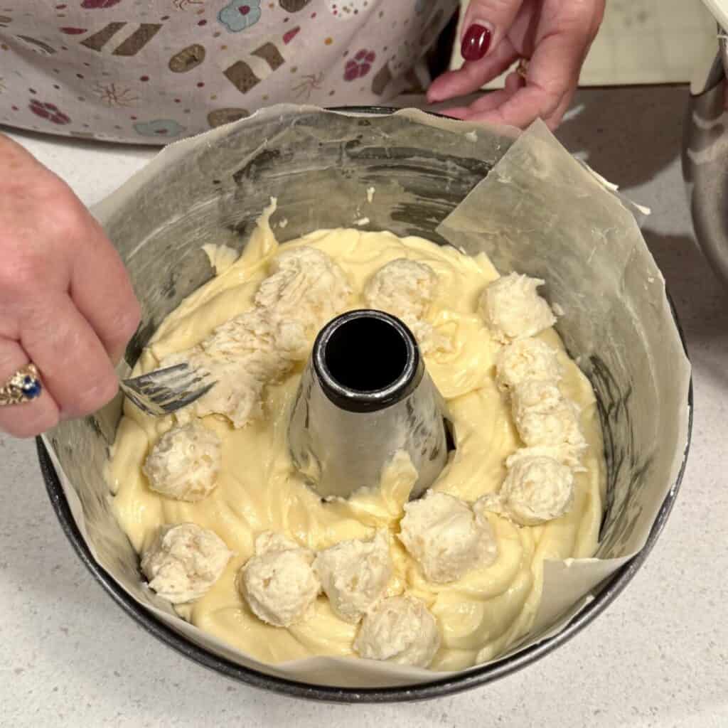 Adding the batter for almond pound cake in a pan.