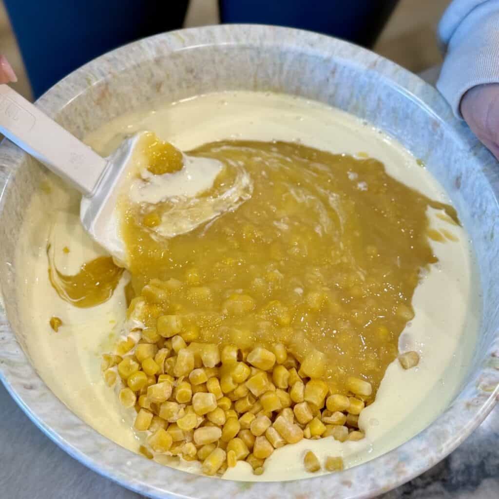 Whisking together the ingredients in a bowl for cheesy corn casserole.