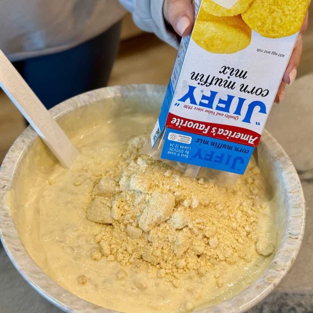 Whisking together the ingredients in a bowl for cheesy corn casserole.