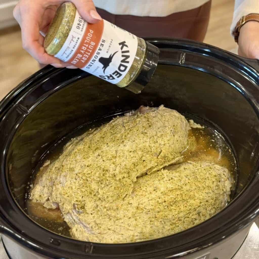 Seasoning a turkey breast in a crockpot.