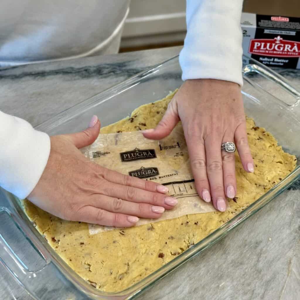 Pressing the crust into a pan for pumpkin gooey butter cake.