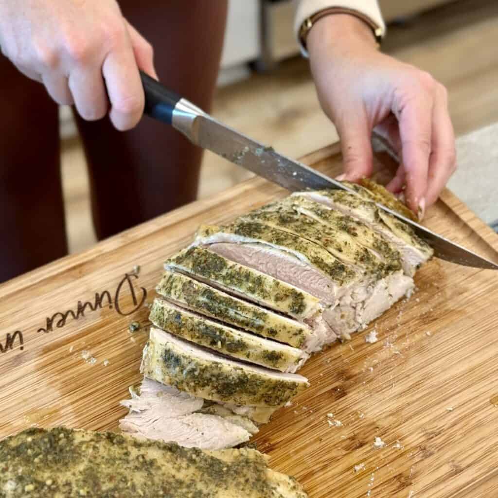 Slicing a cooked turkey breast on a cutting board.