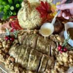 Pouring gravy on a cooked turkey breast.