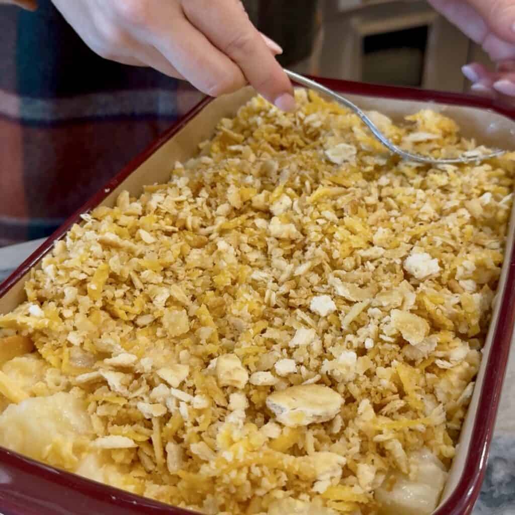 Adding the topping on pineapple casserole recipe.