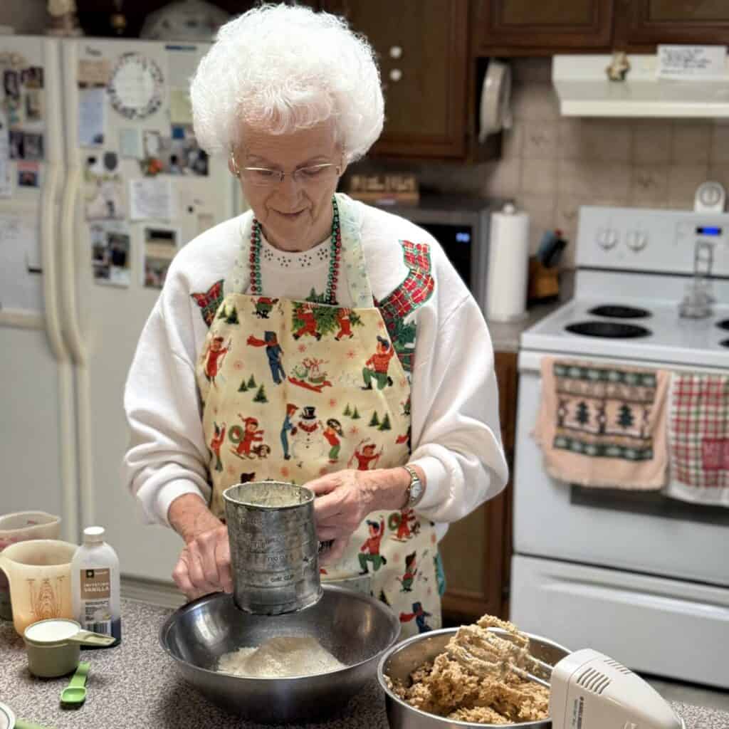 A person sifting flour in a bowl.