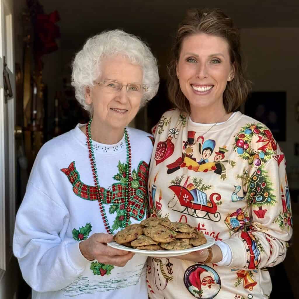 Two people holding a plate of fruitcake cookies.