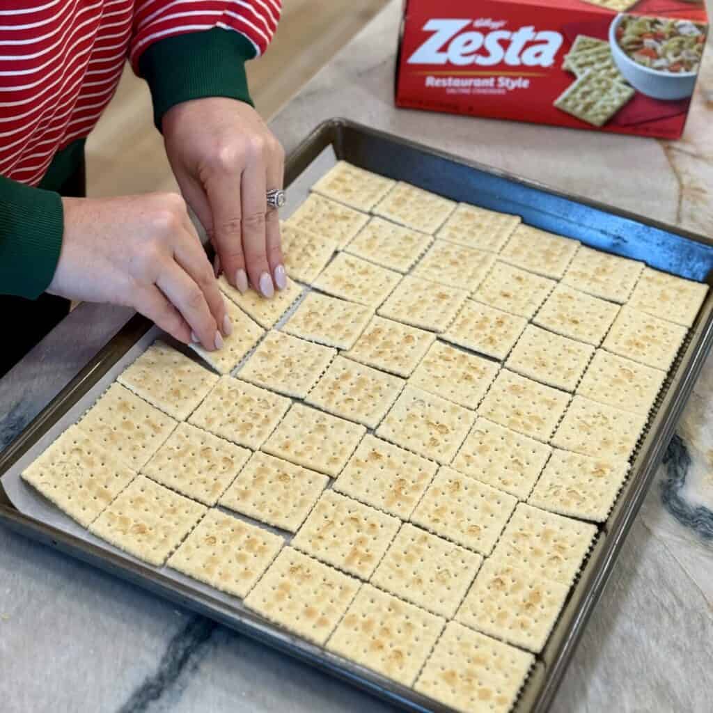 Adding crackers on a sheet pan.