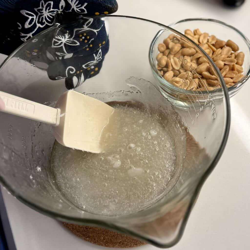 Mixing microwave peanut brittle in a bowl.