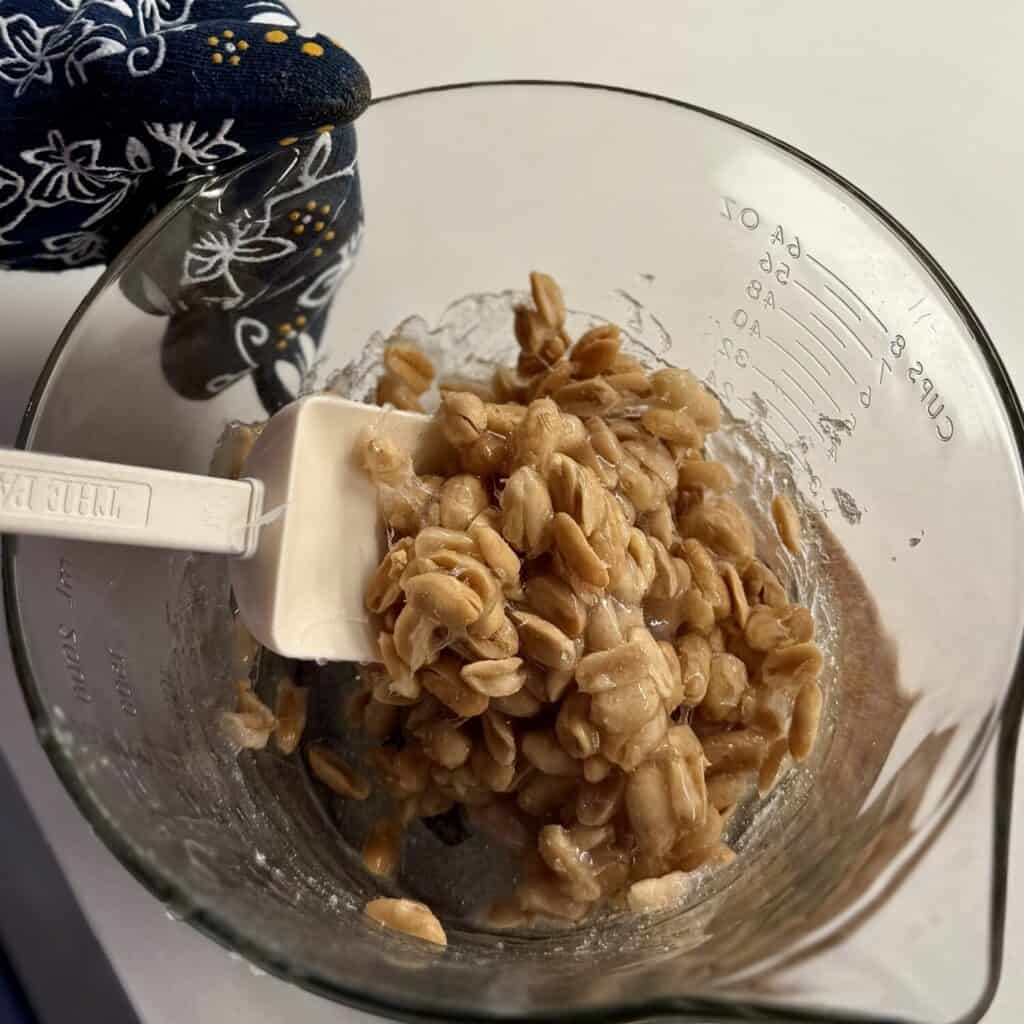 Mixing microwave peanut brittle in a bowl.