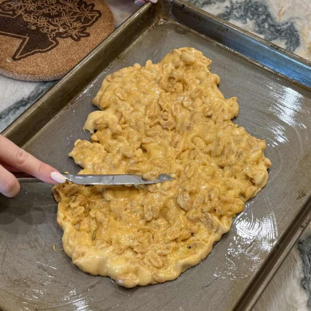 Spreading microwave peanut brittle on a sheet pan..
