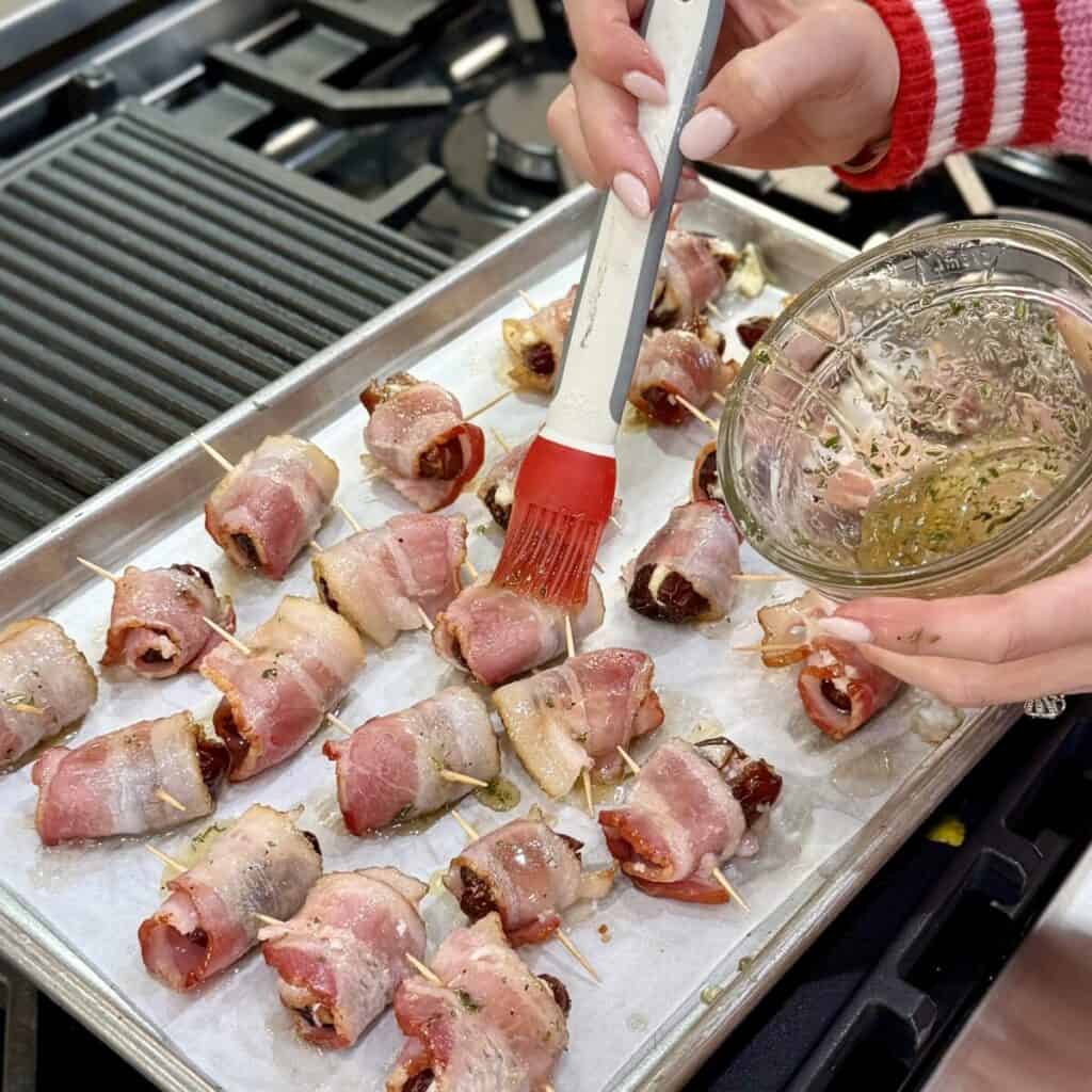 Brushing bacon wrapped dates with honey.