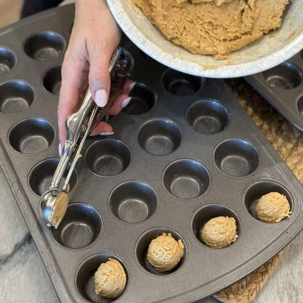 Scooping dough into a mini muffin pan.