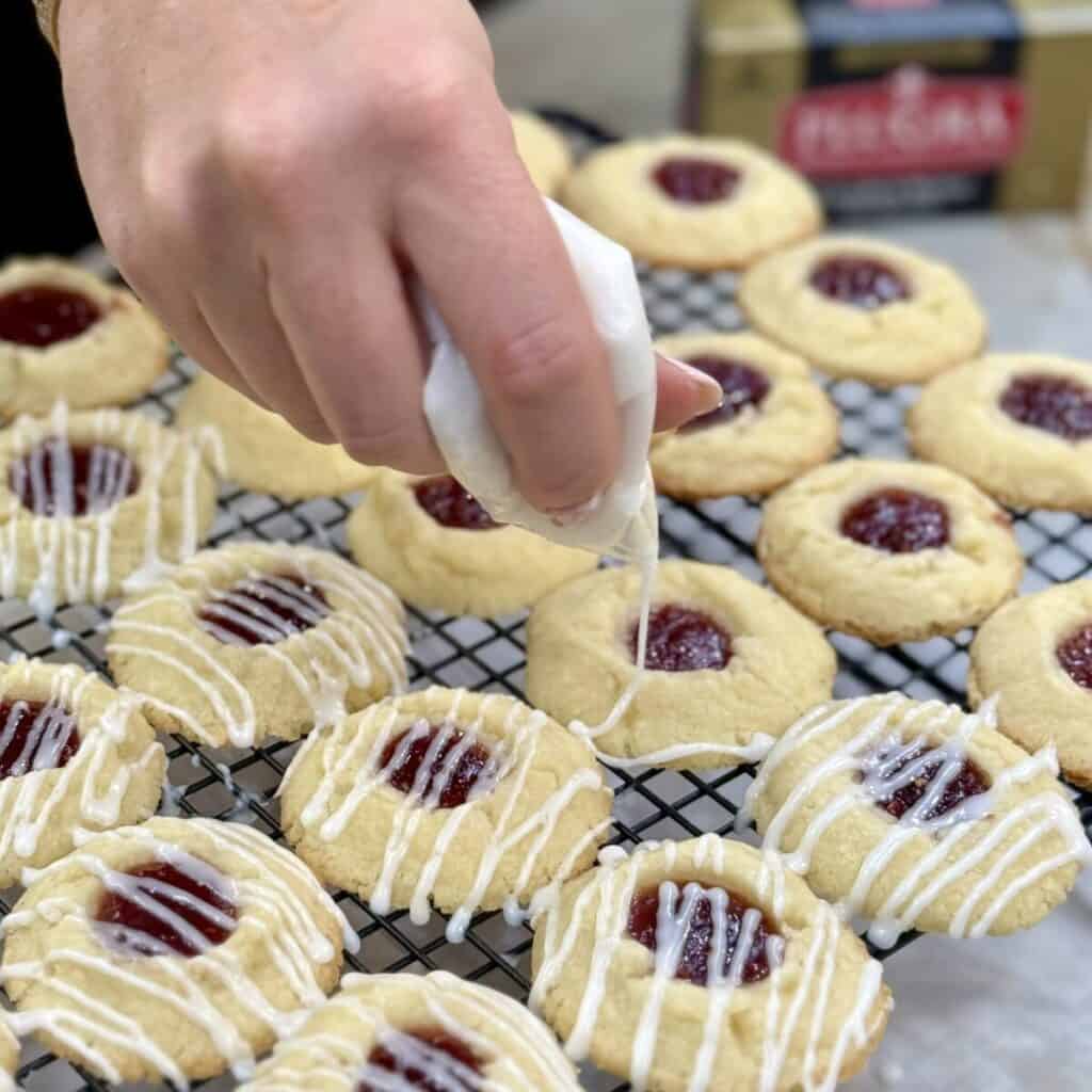Adding glaze to raspberry thumbprint cookies.