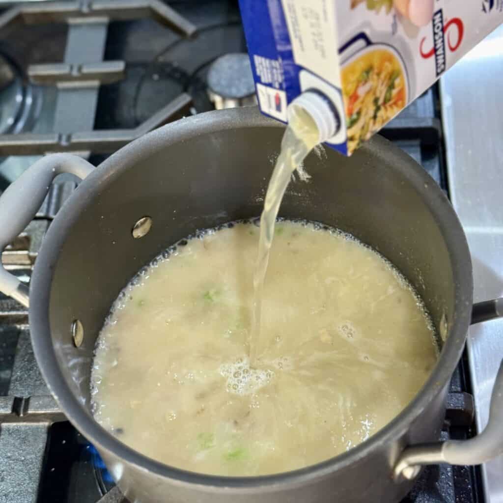 Mixing the ingredients in a pan for buffalo chicken soup.