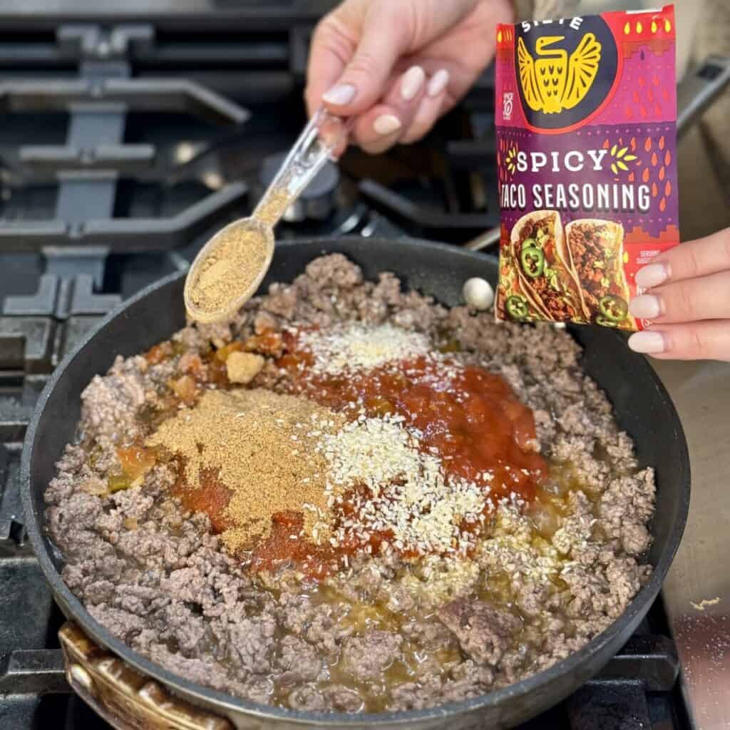 Making the beef mixture in a skillet for taco pie.