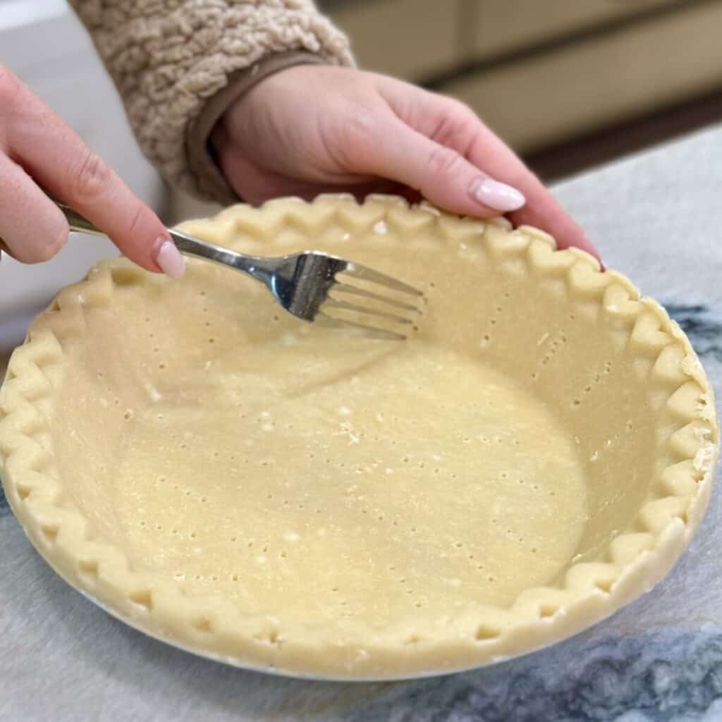 Piercing a pie crust with a fork.