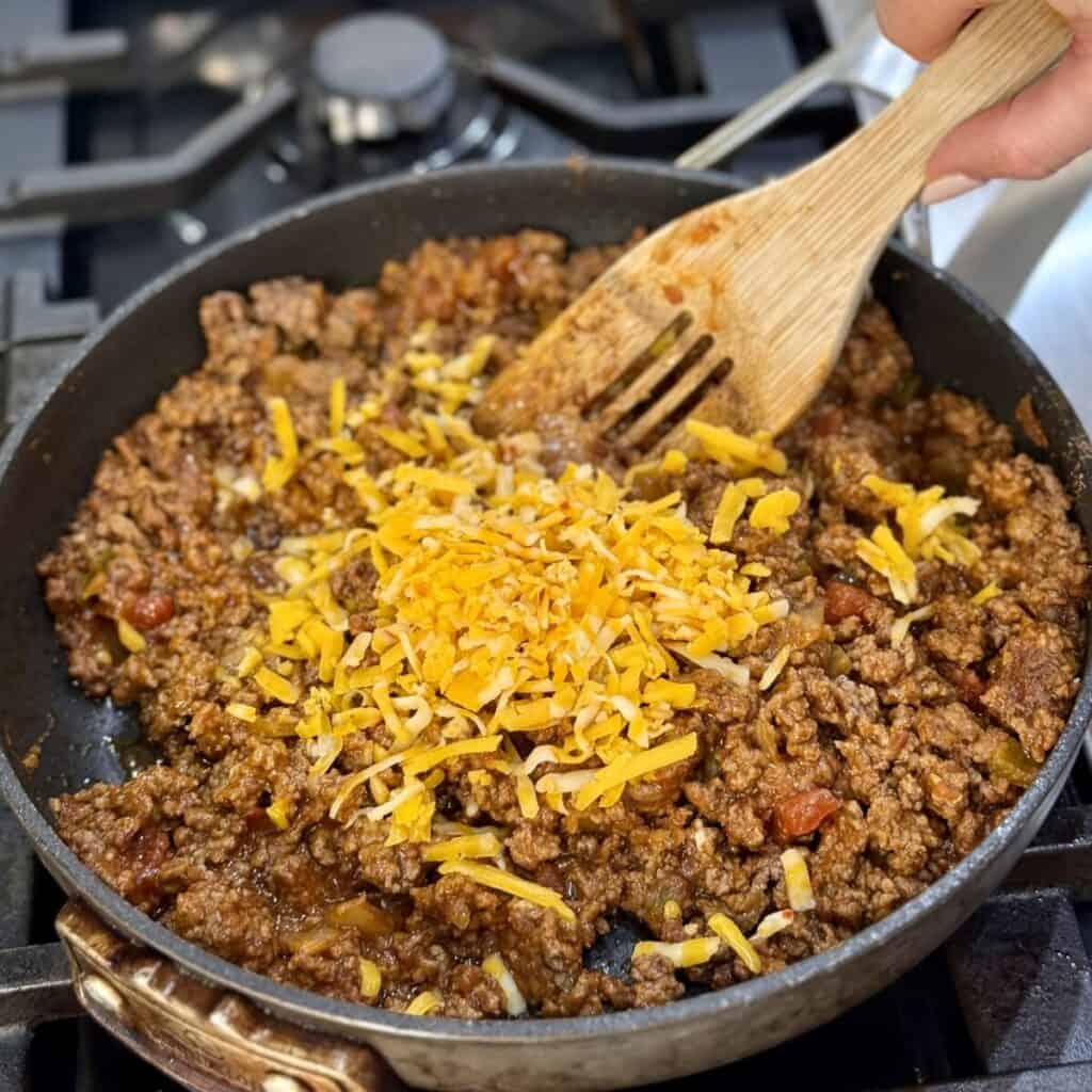 Folding cheese in beef for taco pie.