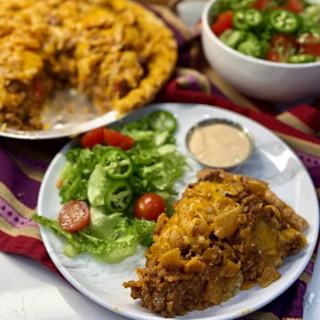 A slice of taco pie on a plate with a salad.