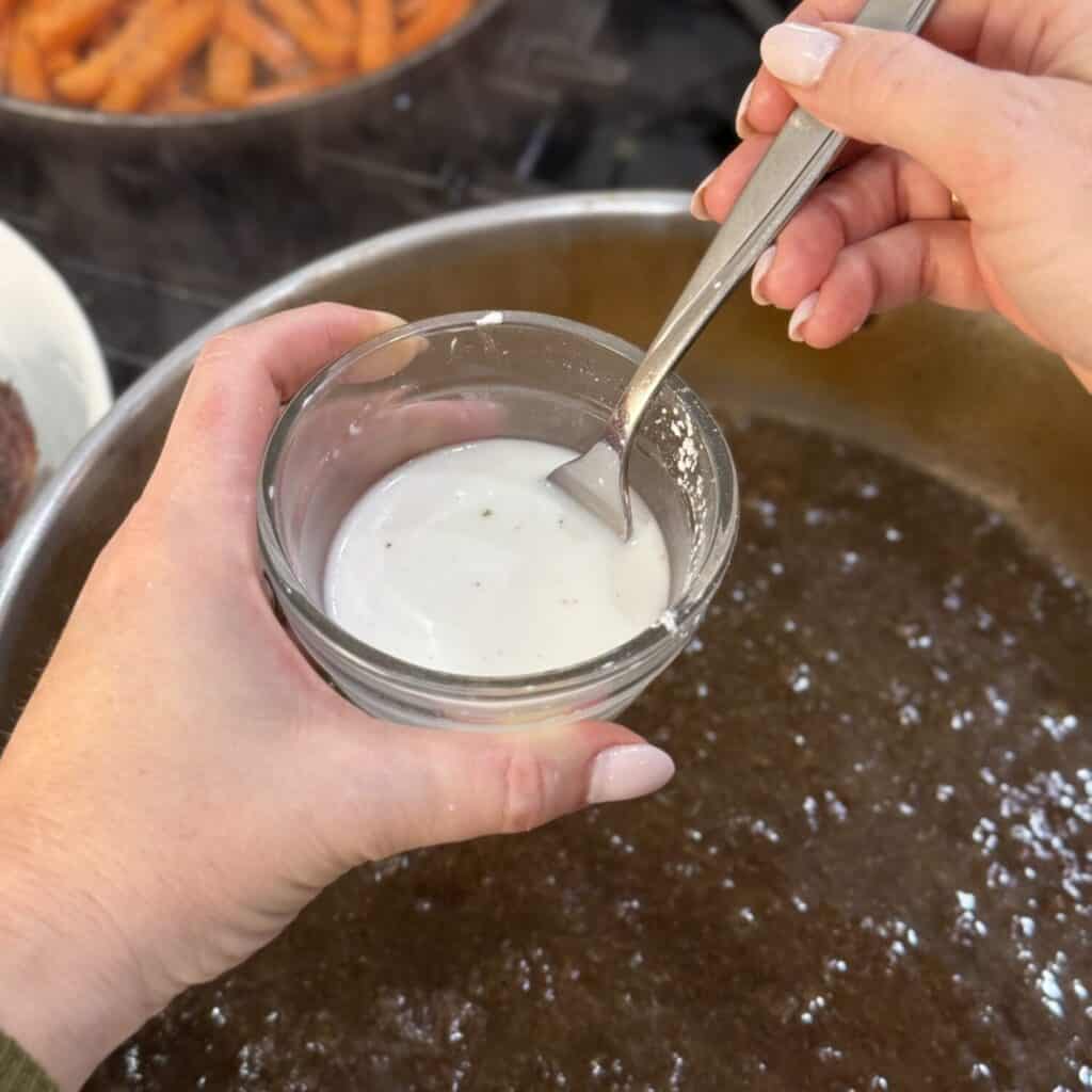 Mixing together a cornstarch slurry in a small bowl.