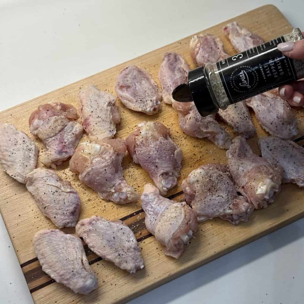 Seasoning wings on a cutting board.