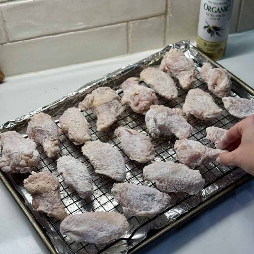 Adding chicken wings to a pan.