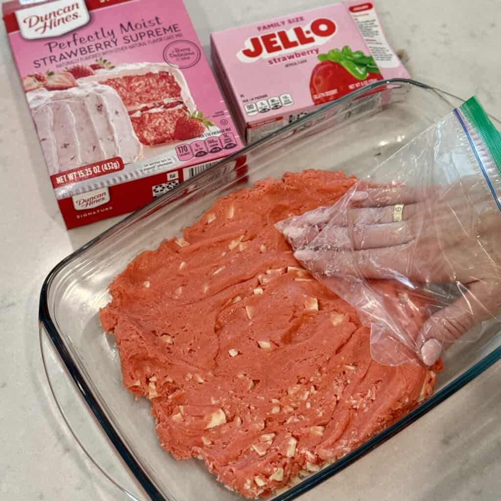 Pressing strawberry brownies in a pan.