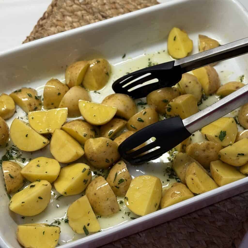 Tossing potatoes with a seasoned olive oil in a pan.