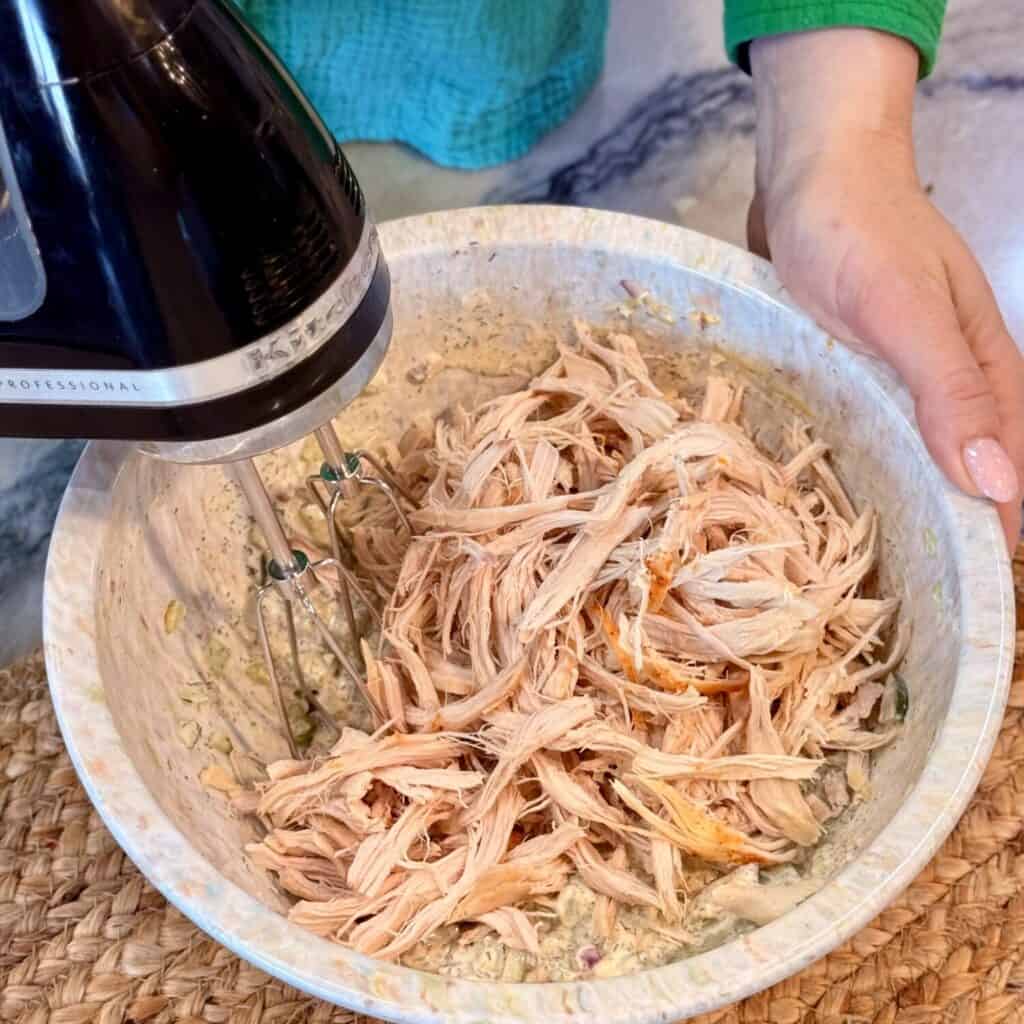 Mixing the ingredients in a bowl for dill pickle chicken salad.