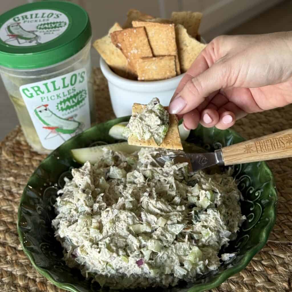 A bowl of dill pickle chicken salad and a serving on a cracker.