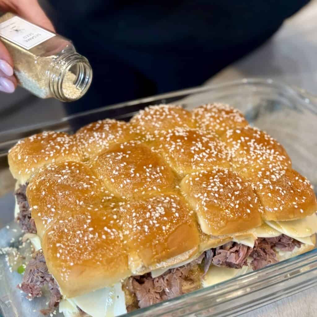 Adding sesame seeds to the top of sliders.