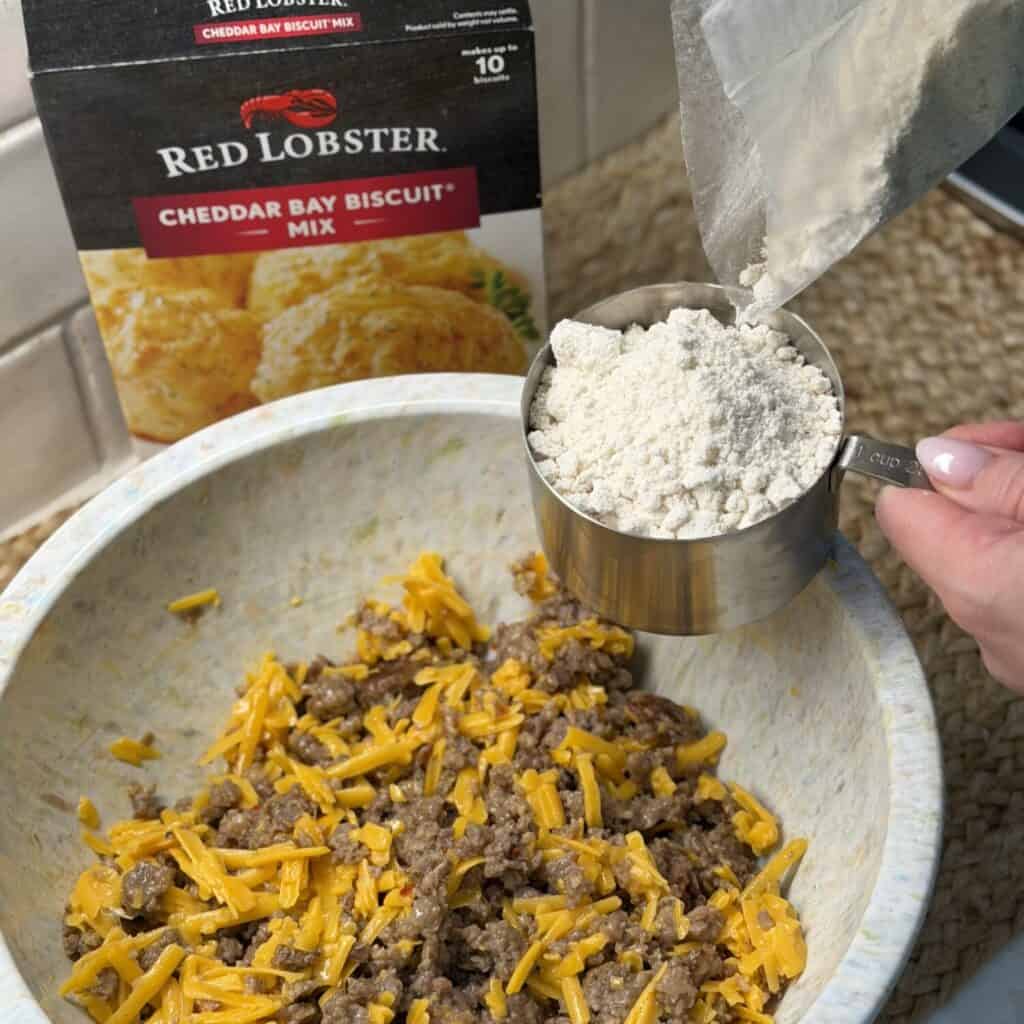 Mixing sausage biscuit muffin batter in a bowl.
