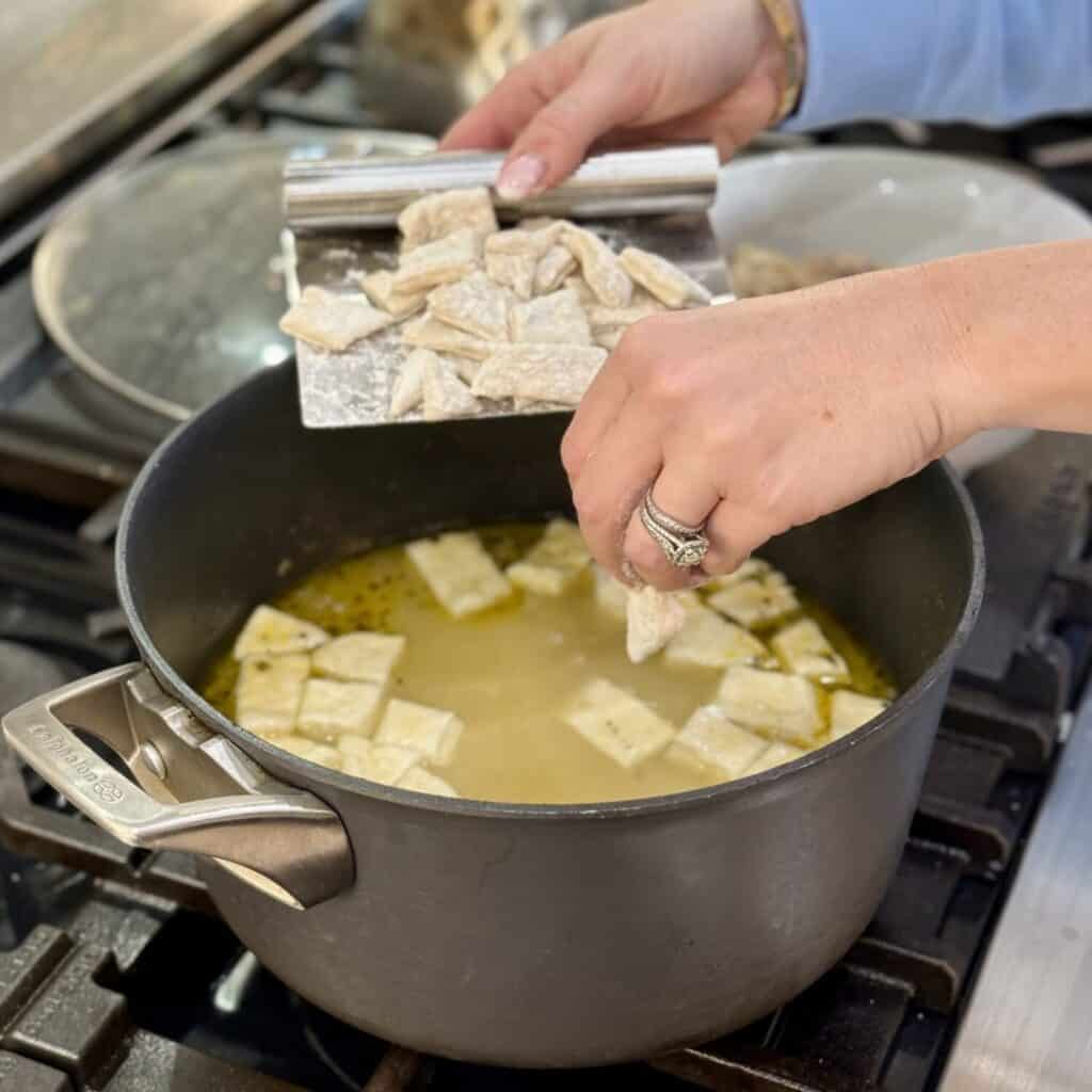 Adding dumplings to a pot for Chicken and Dumplings with Canned Biscuits.