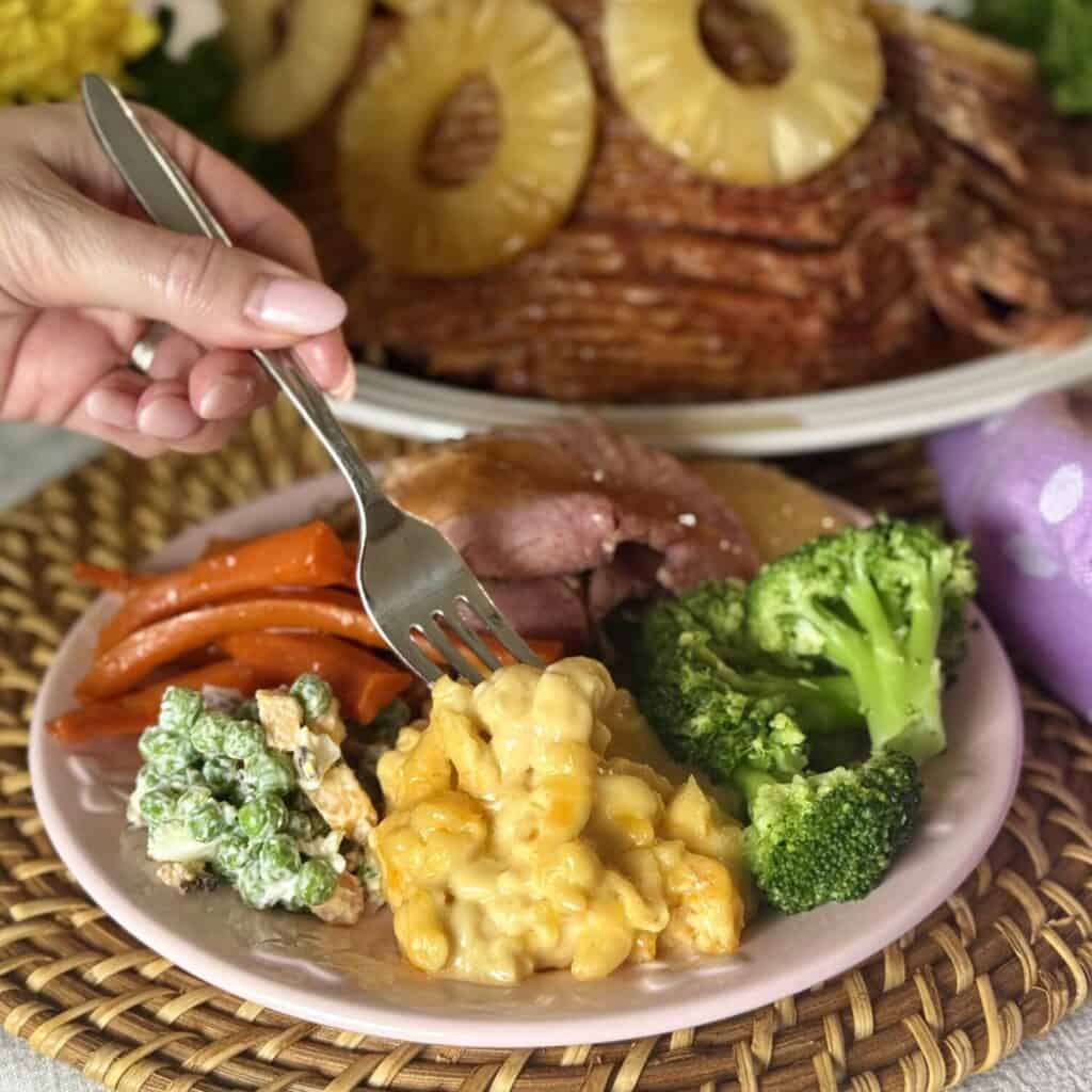 A plate of Mac and cheese, broccoli, ham, carrots, and pea salad.