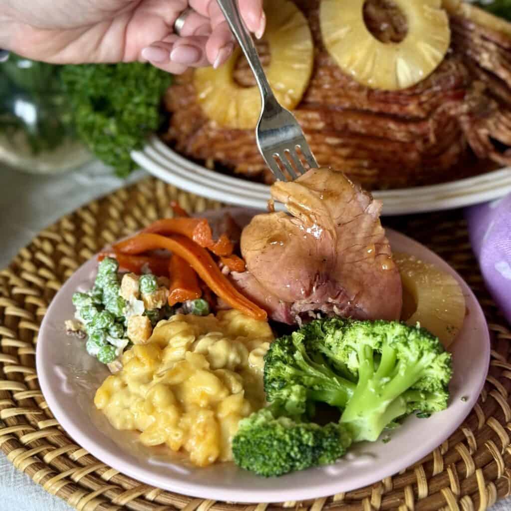 A plate of ham, Mac and cheese, broccoli, pea salad and carrots.