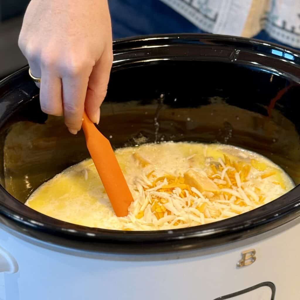 Stirring a cheese sauce in a crockpot.